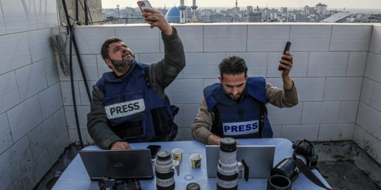 Palestinian journalists attempt to connect to the internet using their phones in Rafah on the southern Gaza Strip on December 27, 2023. ©AFP