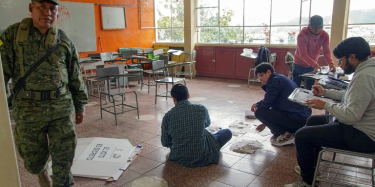 Electoral workers examine ballots while counting votes at a polling station in Cuenca, Ecuador, on October 15, 2023. ©AFP