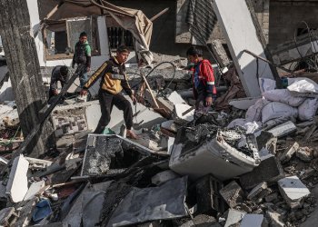 Palestinian boys walk through the rubble of a house destroyed by Israeli bombardment in Rafah, the southern Gaza Strip / ©AFP