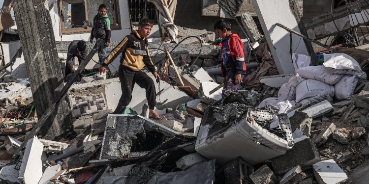 Palestinian boys walk through the rubble of a house destroyed by Israeli bombardment in Rafah, the southern Gaza Strip / ©AFP