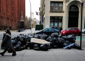 A woman walks past a pile of trash on a Manhattan street on March 19, 2024. ©AFP