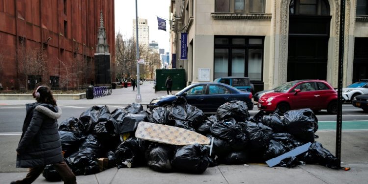 A woman walks past a pile of trash on a Manhattan street on March 19, 2024. ©AFP