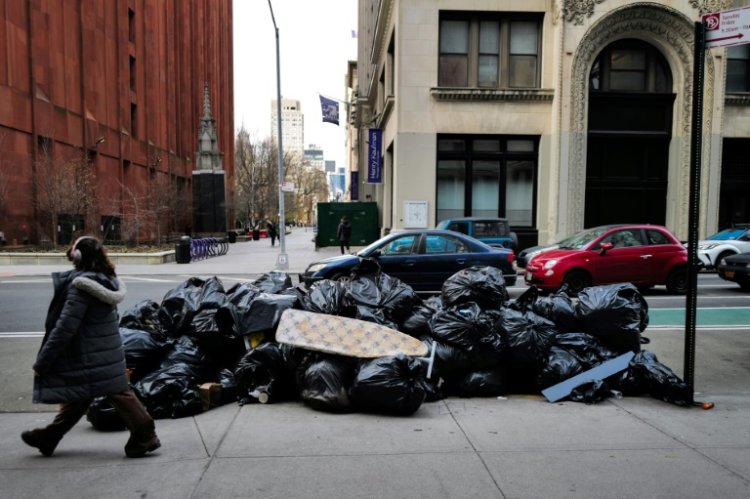 A woman walks past a pile of trash on a Manhattan street on March 19, 2024. ©AFP