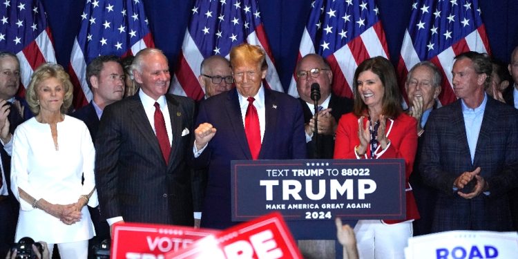 Former US president Donald Trump is flanked by supporters as he celebrates victory in South Carolina -- but there were signs of weakness for his presidential bid in the voting statistics / ©AFP