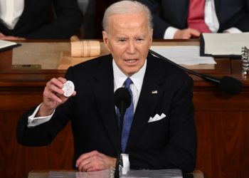 President Joe Biden holds a button that reads 'Say her name: Laken Riley,' during his State of the Union message on March 7, 2024  / ©AFP