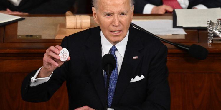 President Joe Biden holds a button that reads 'Say her name: Laken Riley,' during his State of the Union message on March 7, 2024  / ©AFP