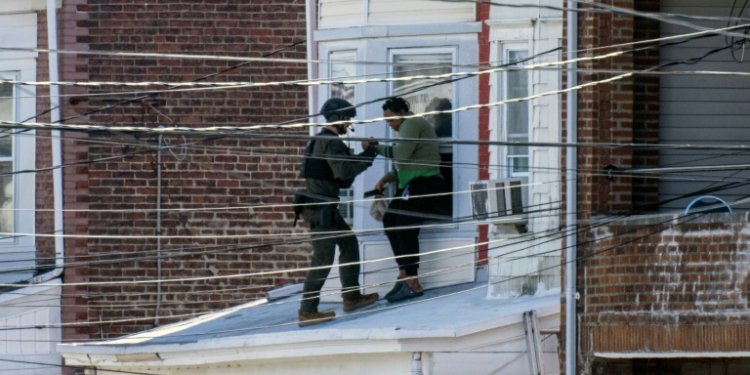 Police remove people from a home in Trenton New Jersey after reports of a gunman, who is suspected of a shooting spree in Pennsylvania. ©AFP