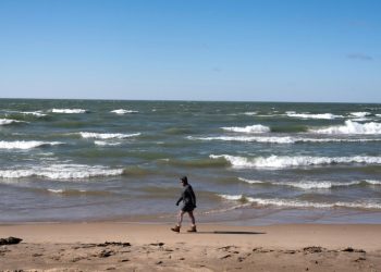 A woman walks along the Lake Michigan shoreline in February in Whiting, Indiana; the Great Lakes shorelines have historically been ice-covered this time of year. ©AFP