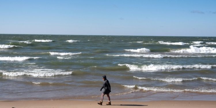 A woman walks along the Lake Michigan shoreline in February in Whiting, Indiana; the Great Lakes shorelines have historically been ice-covered this time of year. ©AFP