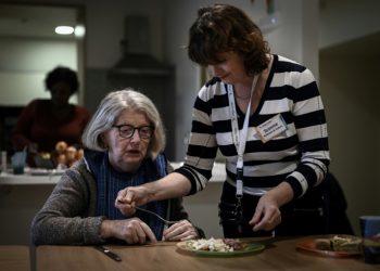 A health care worker (R) tends helps a patient with Alzheimer's eat lunch. ©AFP