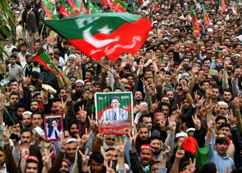 Pakistan Tehreek-e-Insaf (PTI) party supporters hold portraits of former prime minister Imran Khan in a March 2024 protest in Peshawar against alleged rigging of the election against him. ©AFP