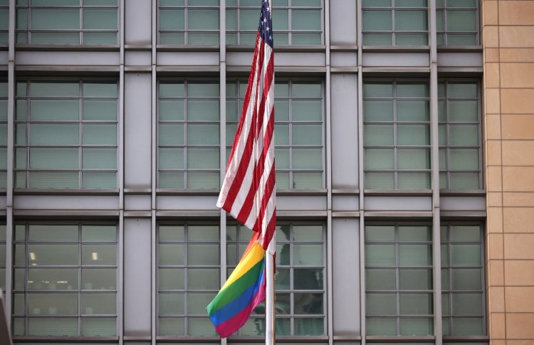 The rainbow flag flies under the US flag at the entrance to the US embassy in Moscow in June 2021 / ©AFP