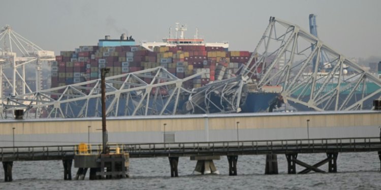 The steel frame of the Francis Scott Key Bridge sits on top of a container ship after the bridge collapsed in Baltimore, Maryland, on March 26, 2024. ©AFP