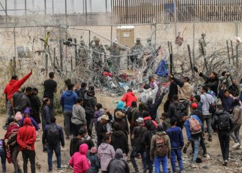 A group of migrants try to cross a barbed wire fence to reach the US from Ciudad Juarez, Mexico on March 20, 2024. ©AFP