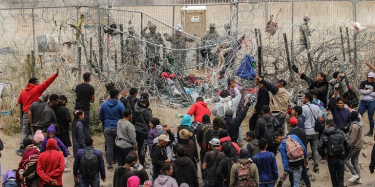 A group of migrants try to cross a barbed wire fence to reach the US from Ciudad Juarez, Mexico on March 20, 2024. ©AFP