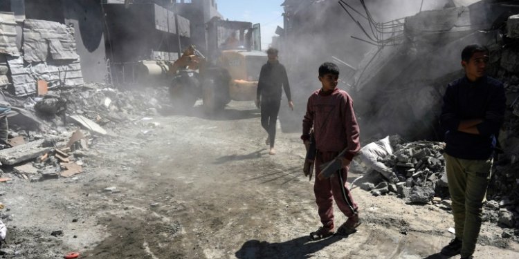 Palestinians clear a road of rubble after a night of Israeli bombing at Nuseirat refugee camp in the central Gaza Strip on Wednesday. ©AFP