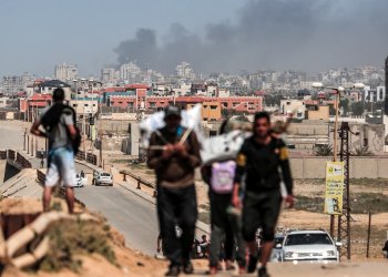 People flee as smoke rises above buildings near the Al-Shifa hospital compound during Israeli bombardment in Gaza City on March 21, 2024 / ©AFP