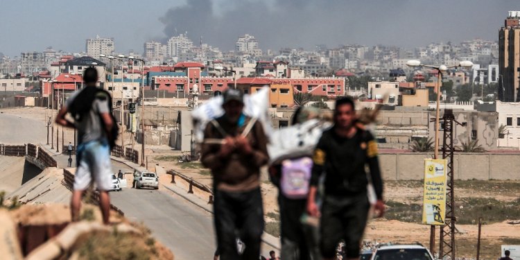 People flee as smoke rises above buildings near the Al-Shifa hospital compound during Israeli bombardment in Gaza City on March 21, 2024 / ©AFP