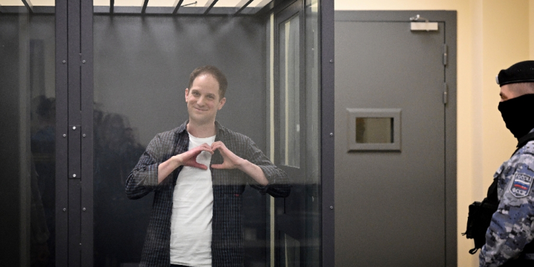 US journalist Evan Gershkovich, arrested on espionage charges, shapes a heart with his hands inside a defendants' cage in a Moscow court / ©AFP