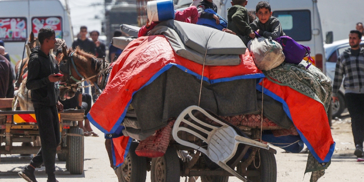 Palestinian children sit on top of their family's belongings as they flee fighting in Nuseirat in central Gaza on a horse-drawn cart. / ©AFP