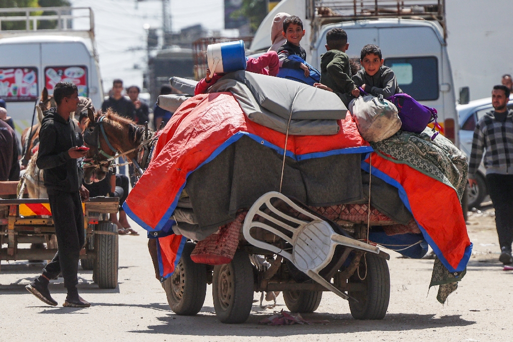 Palestinian children sit on top of their family's belongings as they flee fighting in Nuseirat in central Gaza on a horse-drawn cart. / ©AFP