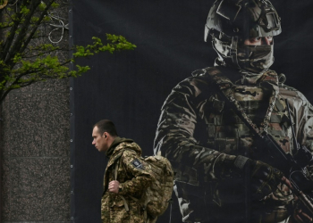 A Ukrainian serviceman walks past a recruiting poster in Kyiv on April 23, 2024. ©AFP