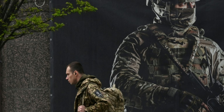 A Ukrainian serviceman walks past a recruiting poster in Kyiv on April 23, 2024. ©AFP