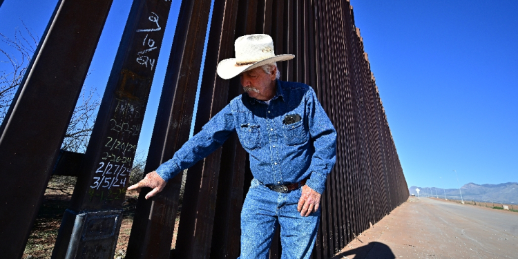 Cattle rancher John Ladd points to dates written on a lower section of the thirty-foot tall US-Mexico border wall marking repairs made after the wall was compromised by migrants crossing into his land from Mexico / ©AFP