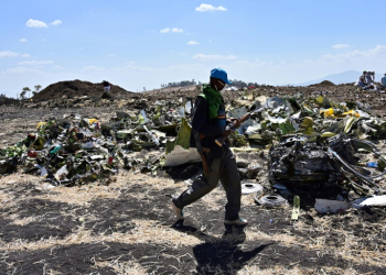 A man walks by a pile of twisted debris at the crash site of an Ethiopian Airways Boeing 737 MAX in March 2019. ©AFP