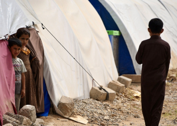 Children stand by tents in April 2024 at the Al-Jadaa camp south of Mosul which houses Iraqi families who have been repatriated from Syria's Al-Hol camp / ©AFP