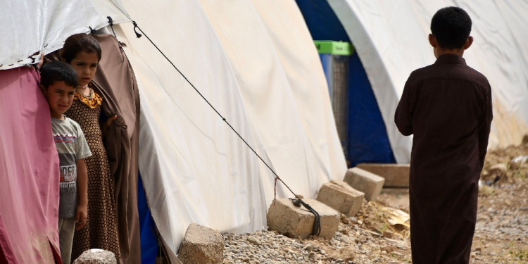 Children stand by tents in April 2024 at the Al-Jadaa camp south of Mosul which houses Iraqi families who have been repatriated from Syria's Al-Hol camp / ©AFP