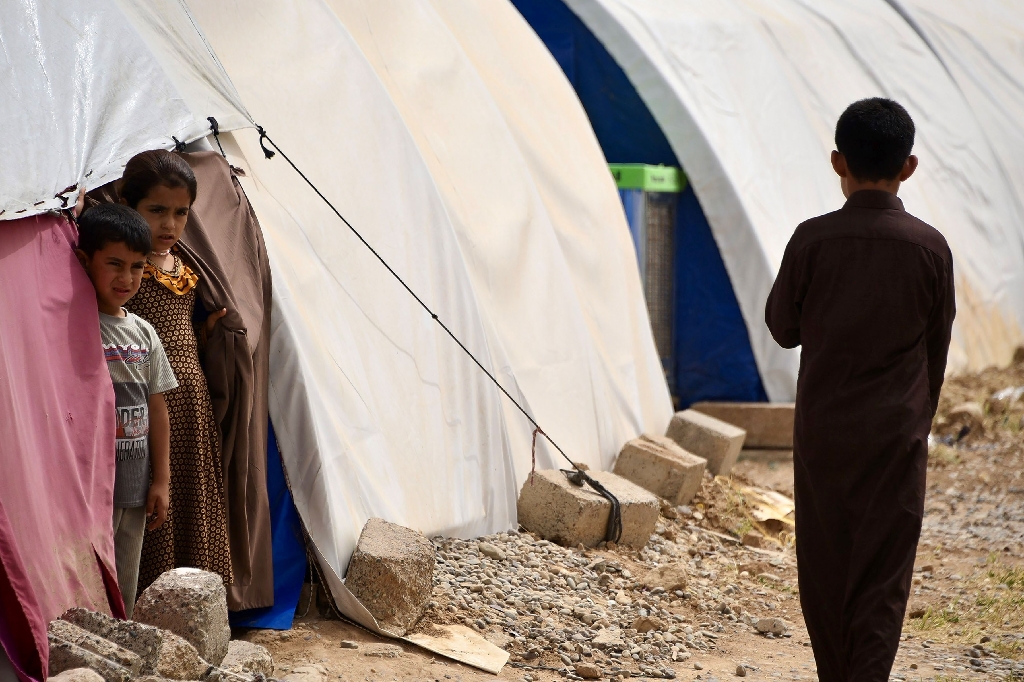 Children stand by tents in April 2024 at the Al-Jadaa camp south of Mosul which houses Iraqi families who have been repatriated from Syria's Al-Hol camp / ©AFP