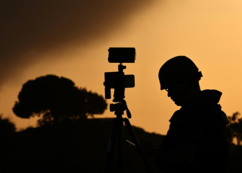 A member of the media stands behind his camera at a spot overlooking the Gaza Strip in the southern Israeli city of Sderot in a file picture taken on October 26, 2023. ©AFP