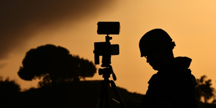 A member of the media stands behind his camera at a spot overlooking the Gaza Strip in the southern Israeli city of Sderot in a file picture taken on October 26, 2023. ©AFP