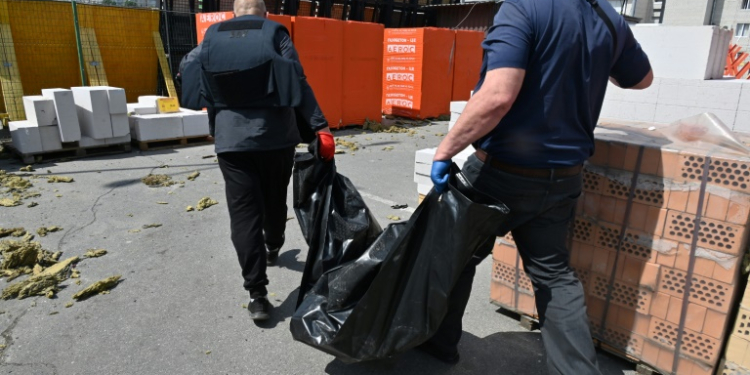 Utility workers carry a bodybag as they evacuate the remains of a victim who was killed in a hardware supermarket in Kharkiv destroyed by a Russian strike, on May 26, 2024, amid the Russian invasion of Ukraine. . ©AFP