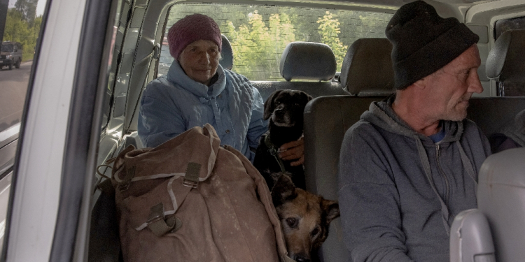 Evacuees from villages in Ukraine's Kharkiv region wait in a car at a checkpoint / ©AFP