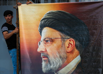 Men hang a huge portrait of Iran's late president Ebrahim Raisi outside the Iranian embassy in Baghdad  / ©AFP