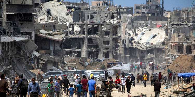 People move past destroyed buildings in Khan Yunis in the southern Gaza Strip  / ©AFP