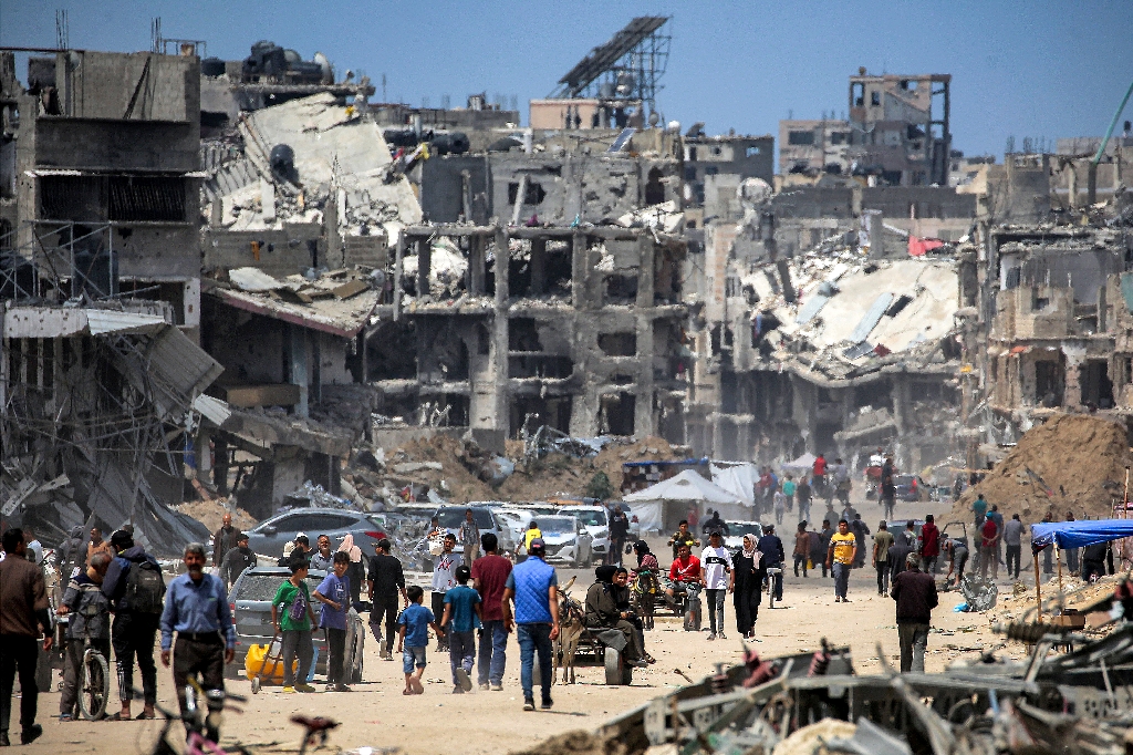 People move past destroyed buildings in Khan Yunis in the southern Gaza Strip  / ©AFP