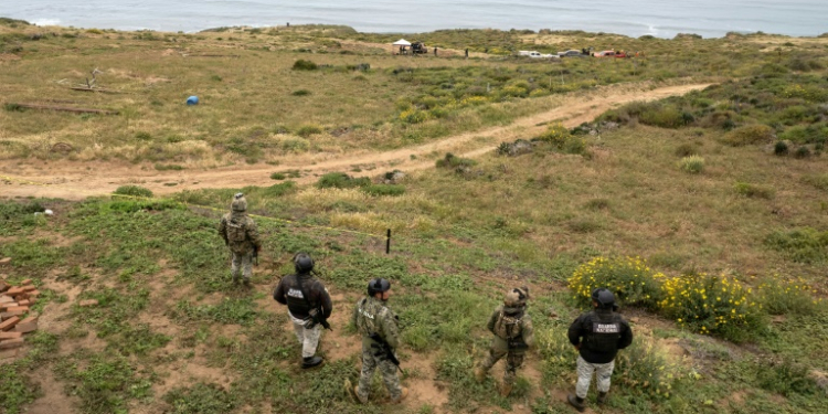 Mexican officers stand guard as rescue and forensics workers as well as prosecutors work at a waterhole where human remains were found near La Bocana Beach, Santo Tomas. ©AFP