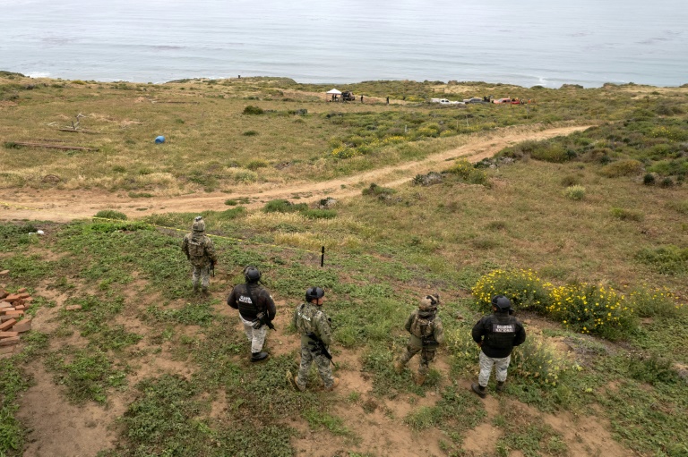 Mexican officers stand guard as rescue and forensics workers as well as prosecutors work at a waterhole where human remains were found near La Bocana Beach, Santo Tomas. ©AFP