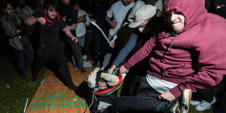 A pro-Palestinian demonstrator (C) is beaten by counter protesters at a pro-Palestinian encampment set up on the UCLA campus in Los Angeles  / ©AFP