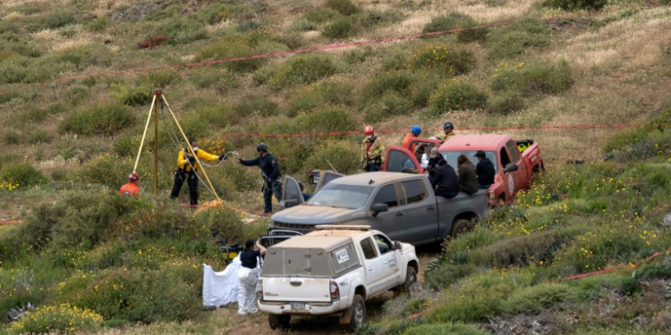 Rescuers are seen working at a clifftop shaft where bodies believed to be those of three missing surfers were discovered. ©AFP