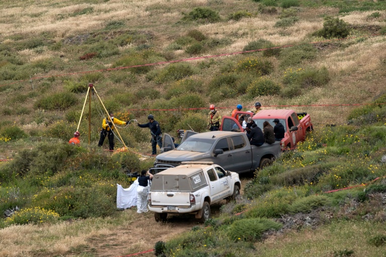 Rescuers are seen working at a clifftop shaft where bodies believed to be those of three missing surfers were discovered. ©AFP