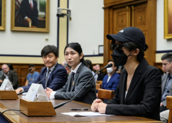 A disguised Columbia University student testifies before the Congressional-Executive Committee on China at a hearing that also included former Tiananmen Square leader Fengsuo Zhou (far left). ©AFP