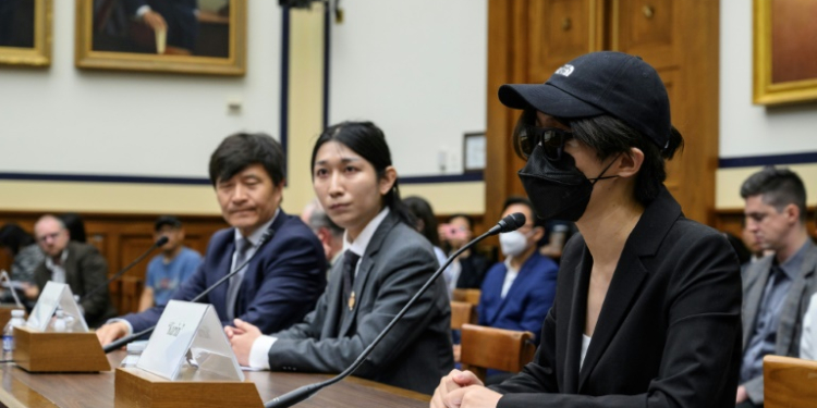 A disguised Columbia University student testifies before the Congressional-Executive Committee on China at a hearing that also included former Tiananmen Square leader Fengsuo Zhou (far left). ©AFP