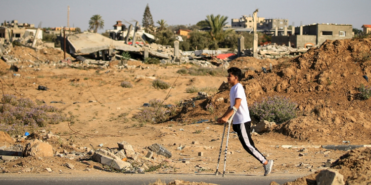 An amputee makes his way past buildings destroyed during Israeli bombardment, at al-Bureij refugee camp, central Gaza  / ©AFP