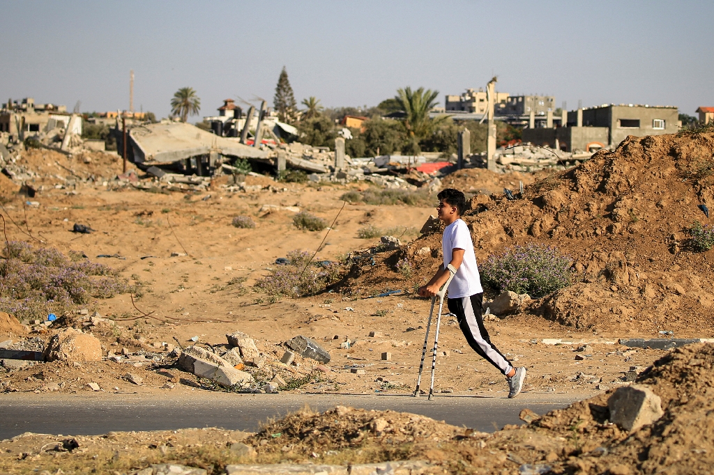 An amputee makes his way past buildings destroyed during Israeli bombardment, at al-Bureij refugee camp, central Gaza  / ©AFP