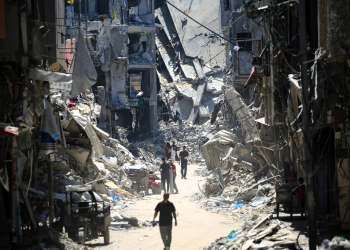 Palestinian men walk along a narrow street past destroyed buildings in Khan Yunis, in the southern Gaza Strip / ©AFP