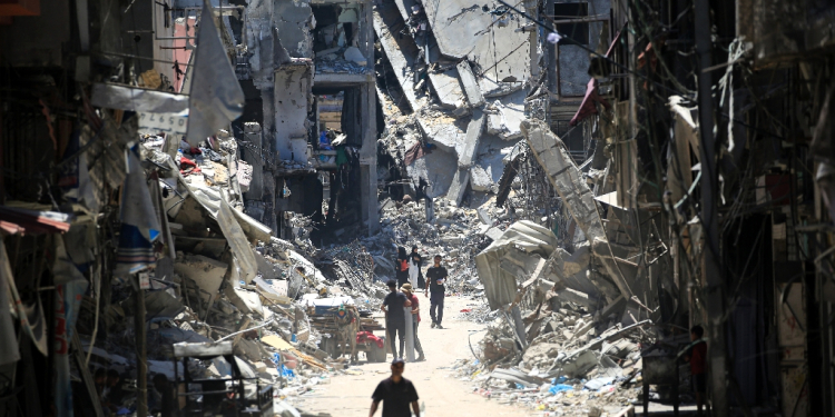 Palestinian men walk along a narrow street past destroyed buildings in Khan Yunis, in the southern Gaza Strip / ©AFP